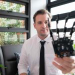 Portrait of a young man holding a robot in his han